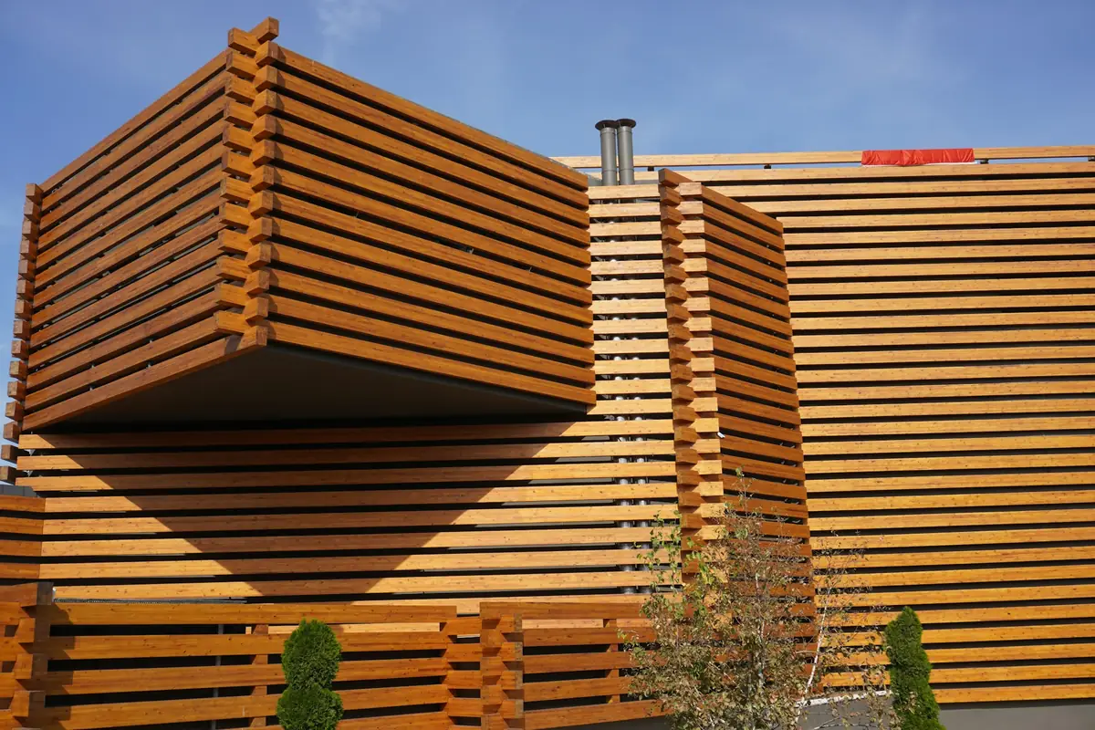 Bâtiment habillé de lames de bois horizontales à claire-voie, sous un ciel bleu