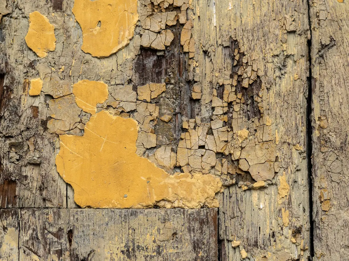 Bois ancien couvert d’une peinture jaune craquelée qui se détache