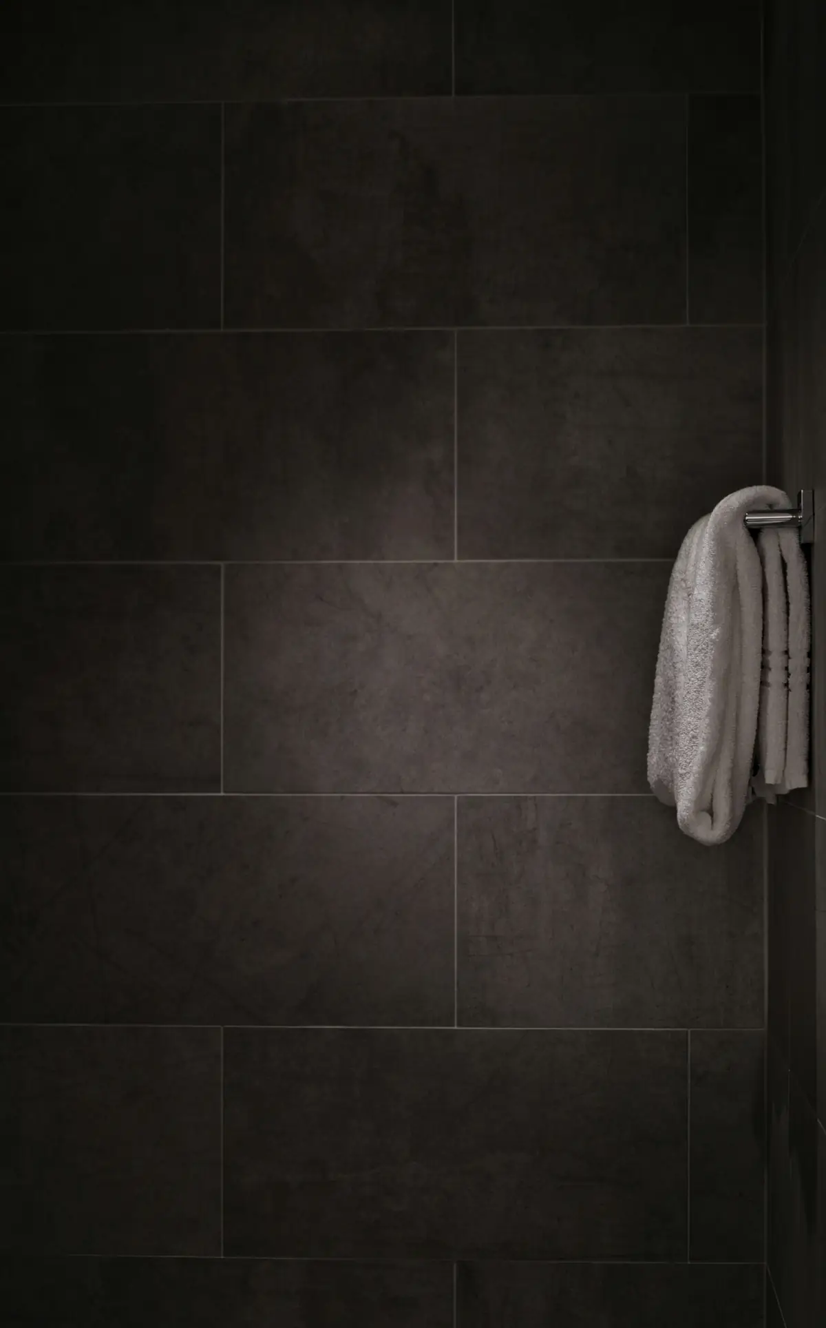 Douche habillée de carreaux anthracite, serviette blanche suspendue