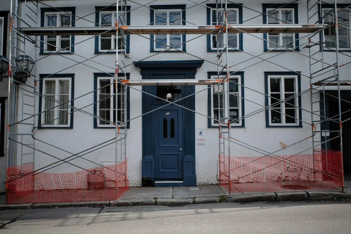 Façade de maison de ville sous échafaudage, porte bleue et fenêtres à petits carreaux