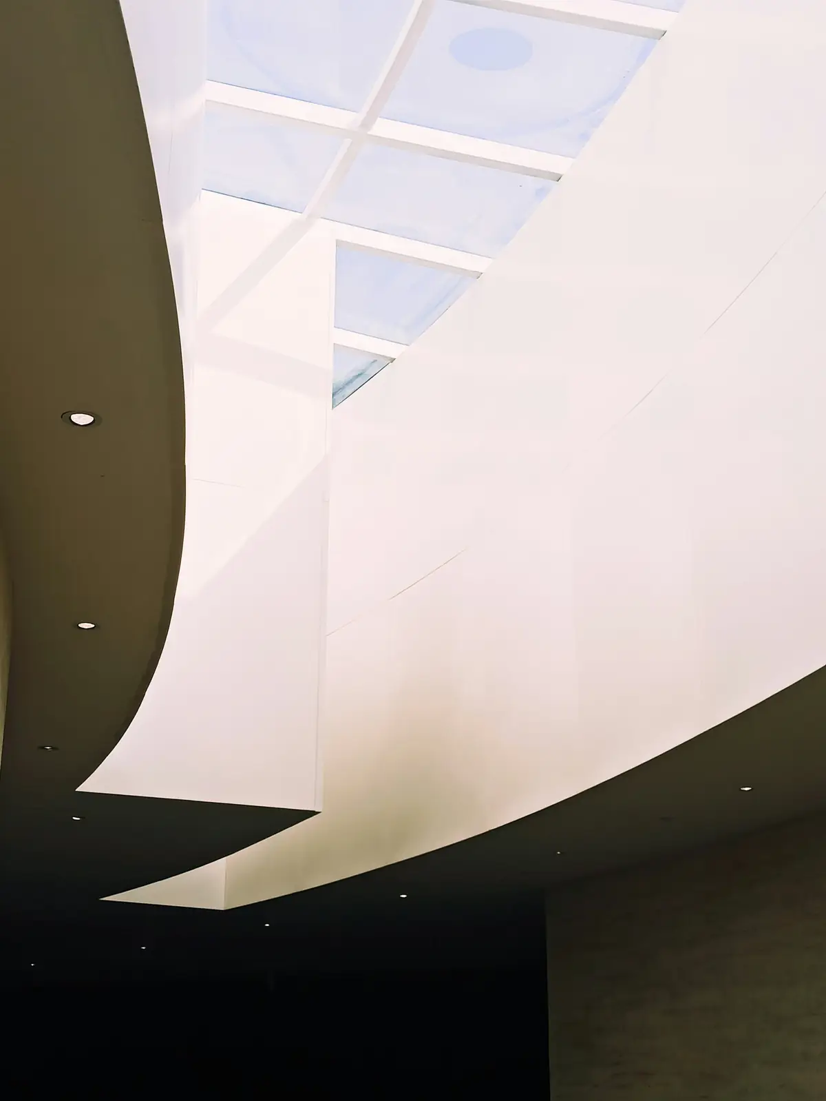 Plafond blanc et lisse qui s’enroule vers une verrière